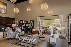 A modern living room with a sofa set, a coffee table, and a bookshelf. - Leopard Sands Kruger Park, Autograph Collection (Mbombela)