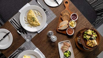 A dining table with various food items, plates, cutlery, and a napkin.