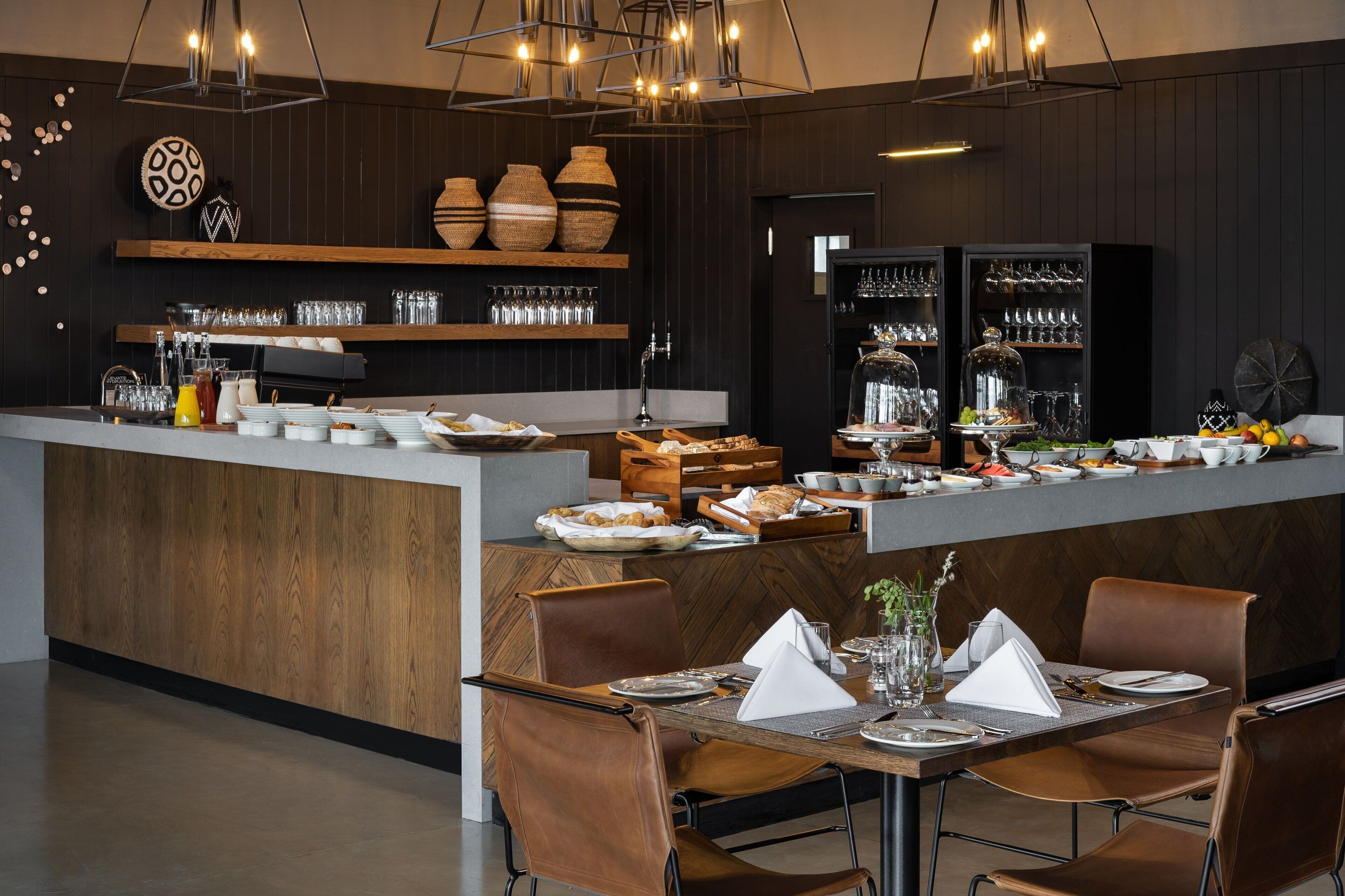 A modern dining area with a central island, wooden paneling, and a variety of dining ware and glassware.