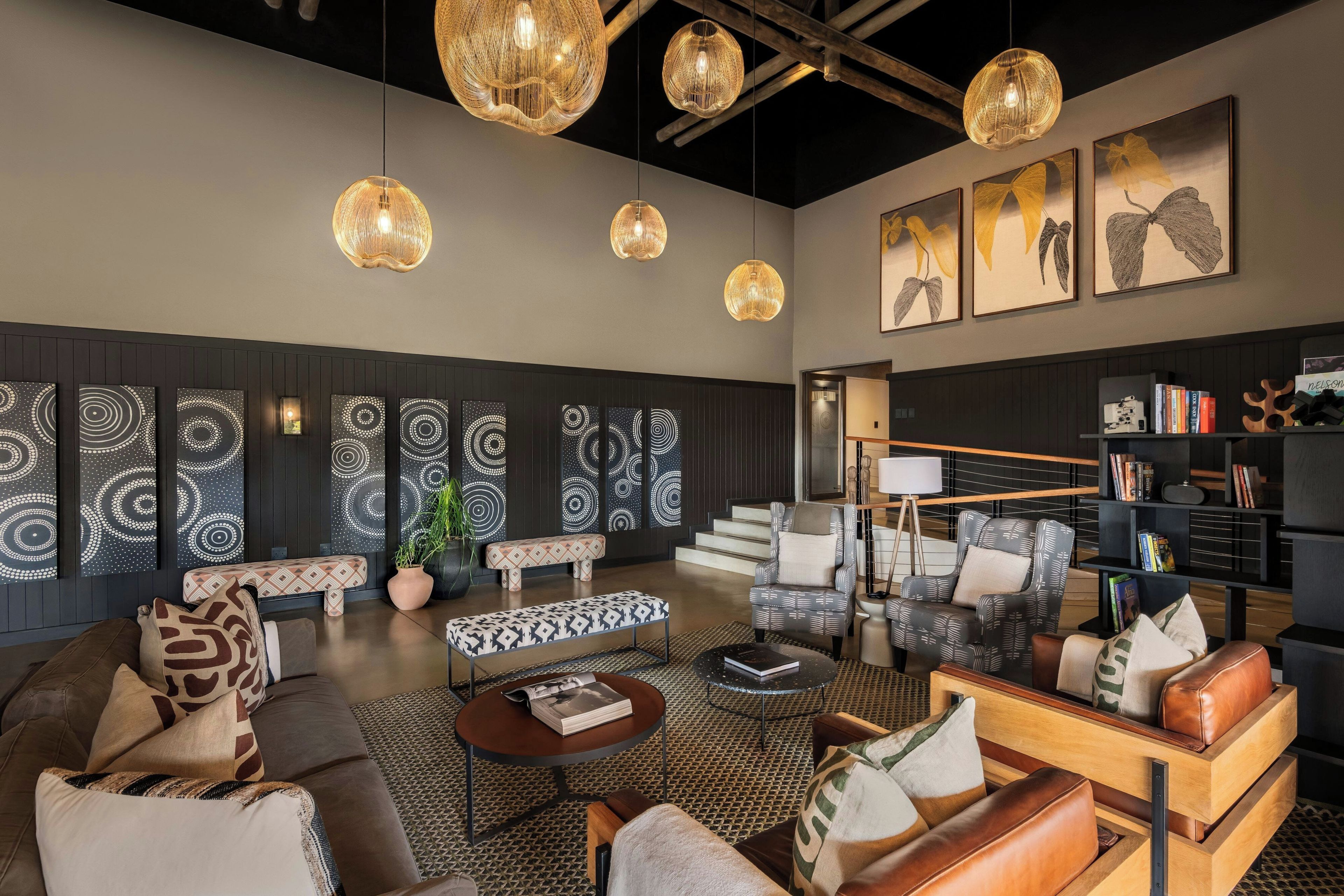 A modern living room with a sofa, armchairs, a coffee table, and a bookshelf.