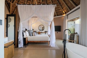 A bedroom with a bed, bedside table, and a large window. - Leopard Sands Kruger Park, Autograph Collection (Mbombela)