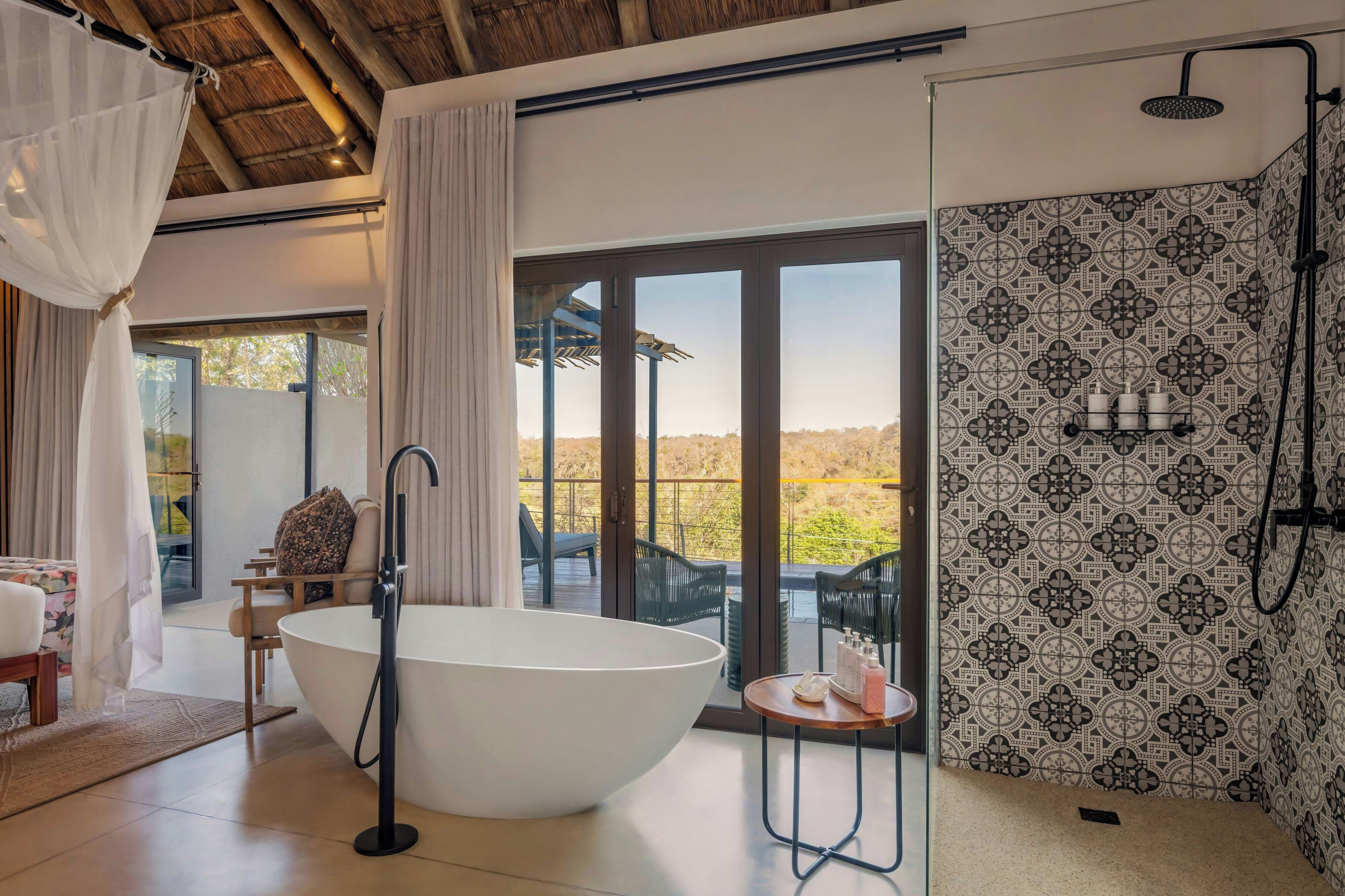 A modern bathroom with a large bathtub, a shower, and a view of the outdoors.