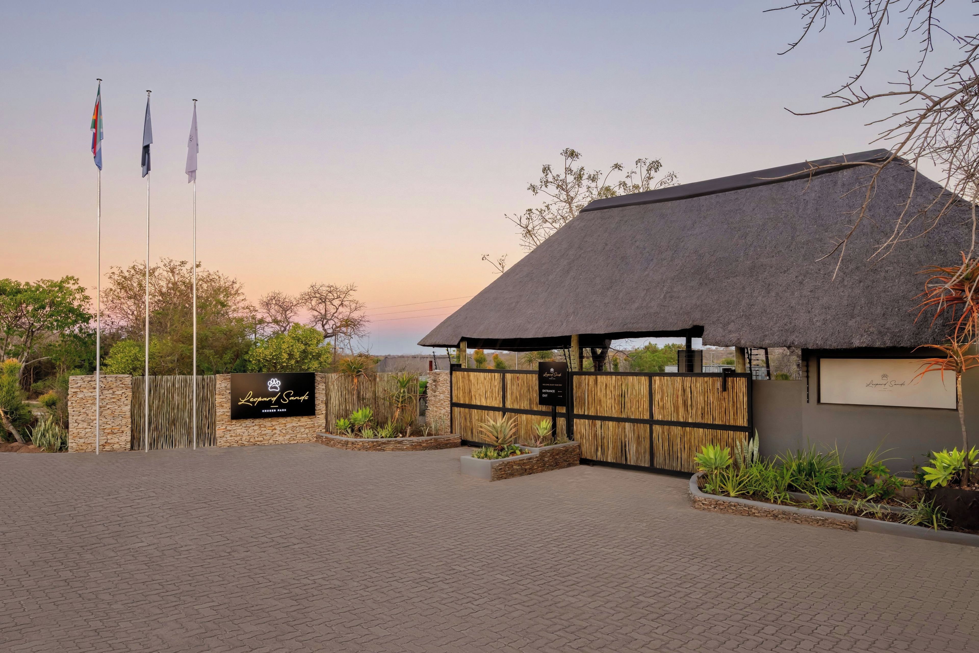 A building with a thatched roof, a stone wall, and a signboard.