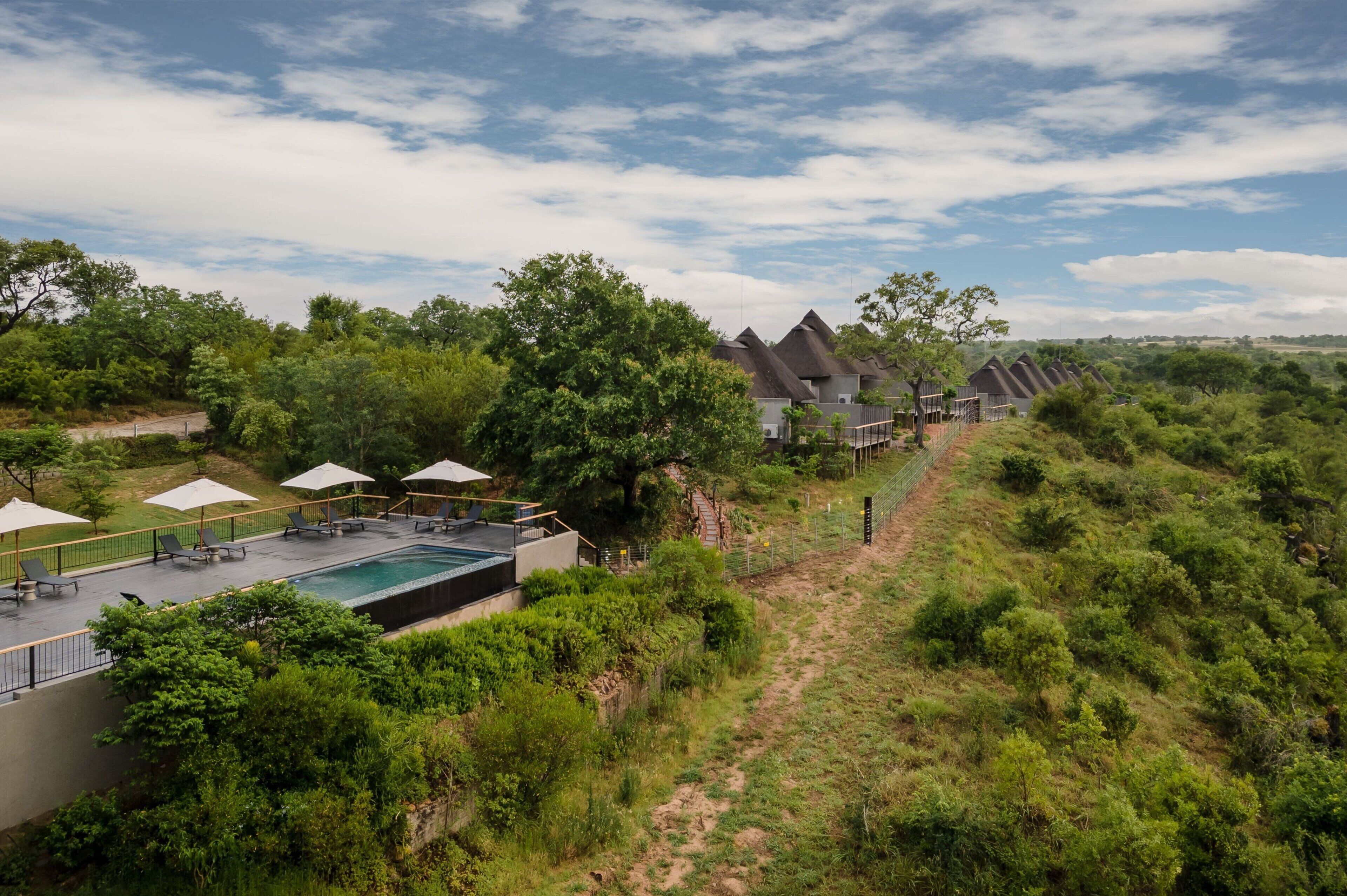 A resort with a swimming pool, lounge chairs, and a scenic view of the surrounding landscape.