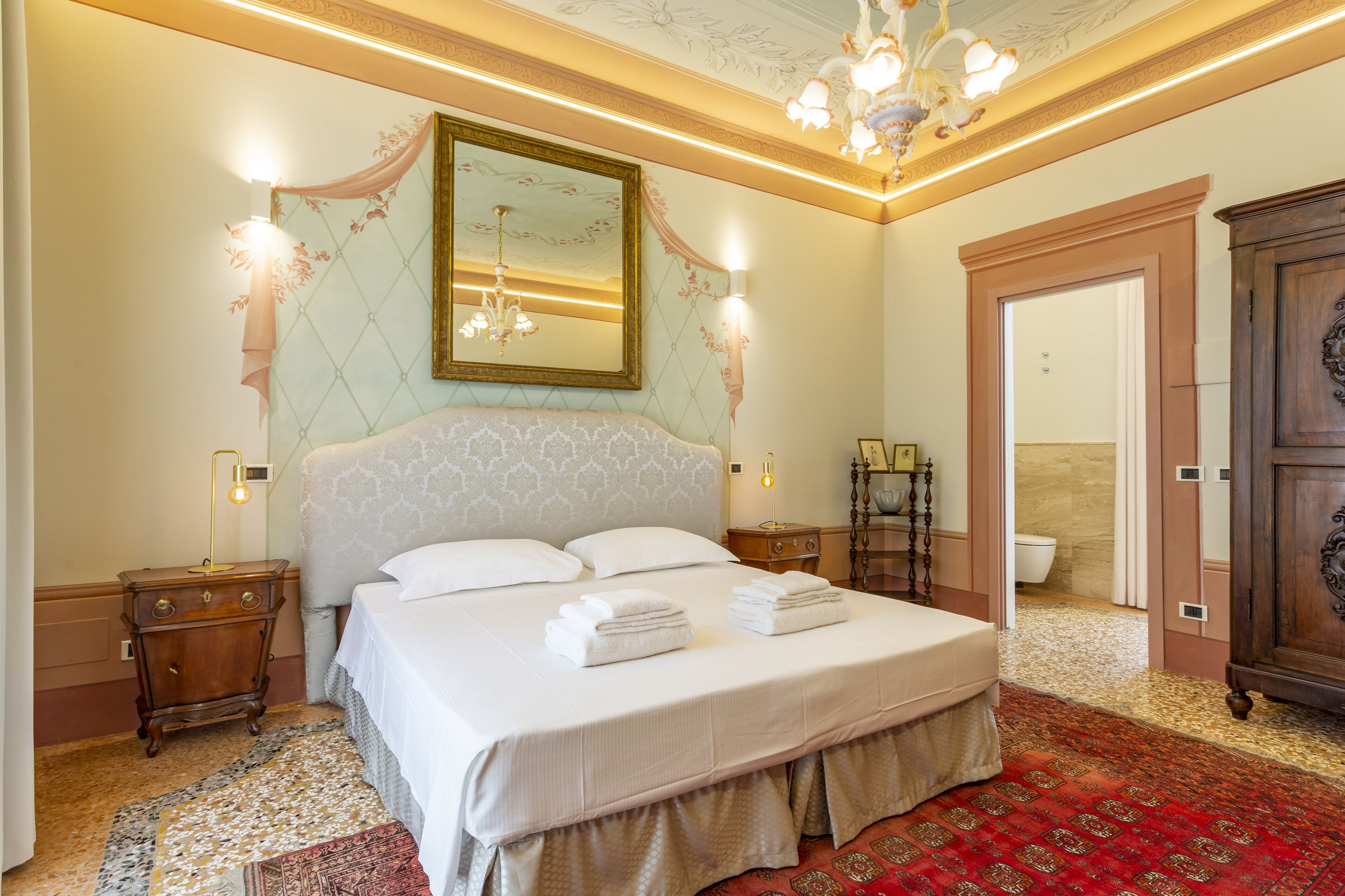 A well-appointed bedroom with a large bed, a chandelier, and a mirror on the wall.