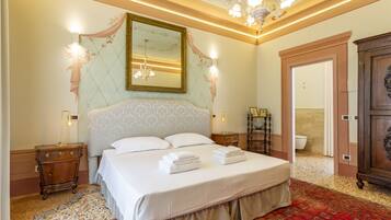A well-appointed bedroom with a large bed, a chandelier, and a mirror on the wall.