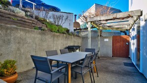 An outdoor patio with a table and chairs, a concrete wall, and a wooden pergola.