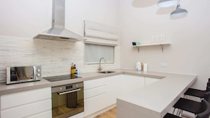 A modern kitchen with a built-in oven, a microwave, a large island, and a window with a view. - Modern & Spacious 1 Bedroom Apartment in London (London)