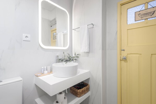A bathroom with a white sink, mirror, and a yellow door.