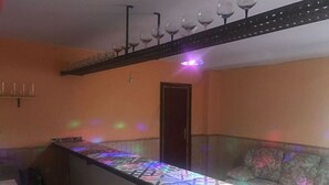 Um quarto com um sofá estampado, uma mesa comprida e um teto com taças de vinho penduradas.