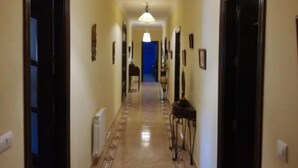 Um corredor com piso estampado, quadros nas paredes e um lustre central.