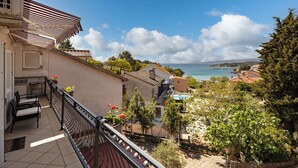 Un balcone con vista sul mare, pavimento in piastrelle e ringhiera.
