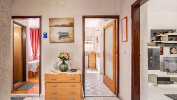 Ein Flur mit einem Holzschrank, einem Blumenstrauß und einem Bild an der Wand.