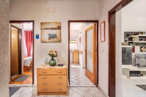 A hallway with a wooden dresser, a vase of flowers, and a painting on the wall.