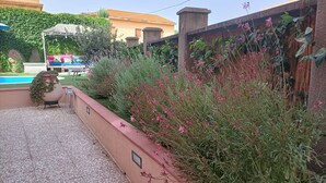 A garden area with a pool, potted plants, and a bamboo fence. - Dependence 2 Fronte Piscina in Centro Storico (Oristano)