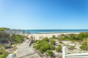 Une promenade en bois menant à une plage, avec un ciel dégagé.