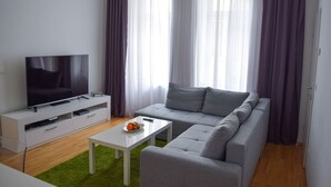 A modern living room with a flat-screen TV, grey sofa, white coffee table, and a green rug. - Modern apartment in Vienna near Danube (Vienna)