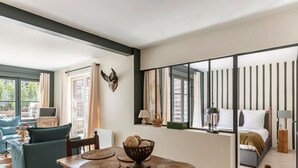 A modern room with a dining area, a bed with a view, and a large window with curtains. - La Terrasse de Pom | Cozy Comfort | City Center | 2 Guests (Honfleur)