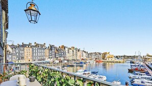 Une vue sur le front de mer, avec des bâtiments, un port de plaisance et une rue bordée d’un café.