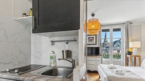 Une cuisine de taille réduite, équipée d’un évier, d’une cuisinière et d’un luminaire orange suspendu.