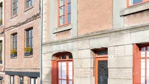 Un edificio de varios pisos con ventanas de marco rojo y fachada de piedra.