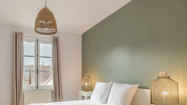 Un dormitorio con cama, ventana con cortinas, lámpara colgante y lámparas de noche.