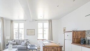 Una sala moderna con un sofá, una mesa de comedor y una zona de cocina con un armario de madera.