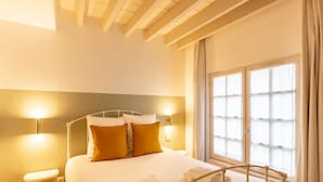A hotel room with a bed, two bedside lamps, a window with curtains, and a wooden ceiling. - La Belle Place | City Center | 4 Guests (Honfleur)