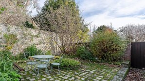 A garden patio with a stone-tiled floor and metal furniture. - Couleur Corail Studio – Peaceful gem & shared yard – Central Honfleur (Honfleur)