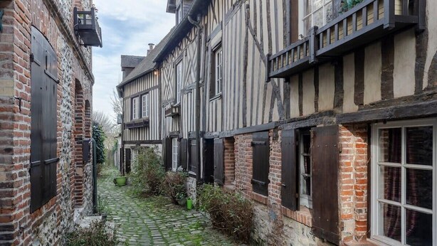 A narrow cobblestone alley between traditional half-timbered buildings with exposed brickwork and timber framing. - Couleur Corail Studio – Peaceful gem & shared yard – Central Honfleur (Honfleur)
