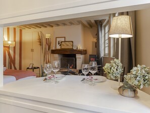 Une chambre d’hôtel avec une table à manger dressée pour deux personnes, un vase rempli de fleurs et une cheminée en arrière-plan.
