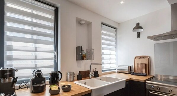 Een moderne keuken met een groot raam, een spoelbak, een fornuis en een koffiezetapparaat.