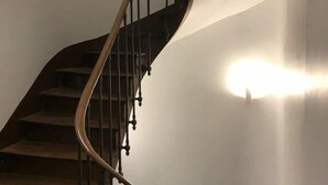 Una scala a chiocciola con ringhiera in legno e balaustre in metallo, a contrasto con una parete liscia.