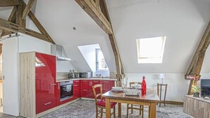 Una cucina con mobili rossi, un tavolo da pranzo in legno e un televisore su un supporto in legno.