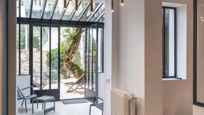 A modern interior with a unique ceiling light fixture, large windows, and a view of an outdoor area with seating.