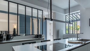 A modern kitchen with a large island, a built-in oven, and a large window providing natural light.