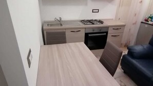 Una cucina compatta con un tavolo da pranzo, pensili e un piano cottura a gas.