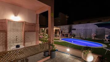 A pool area with a blue pool, a wooden deck, and a seating area with a table and chairs.