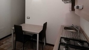 Una cucina funzionale con piano cottura a gas, lavello e un piccolo tavolo da pranzo con due sedie.