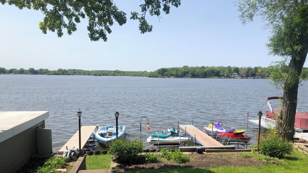 A lakeside dock with boats, a wooden pier, and a grassy area with trees.