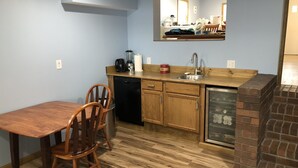 A compact kitchen with wooden cabinets, a dishwasher, a sink, and a brick oven.