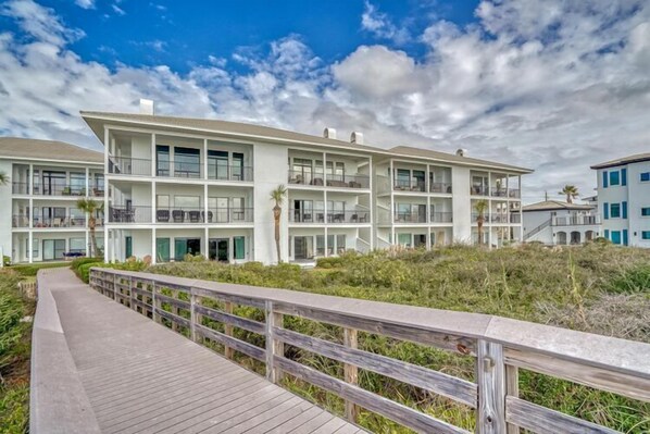 A multi-story hotel with balconies, a wooden boardwalk, and a beach view. - Take your time at Dune Thyme / Gulf Front Condo / Steps to Sand / Community Pool (Santa Rosa Beach)
