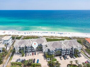 A beachfront hotel with a parking lot, beach view, and a sign indicating a location. - Take your time at Dune Thyme / Gulf Front Condo / Steps to Sand / Community Pool (Santa Rosa Beach)