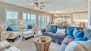 A spacious living room with a gray sofa, a round coffee table, and a ceiling fan.