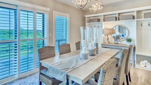 A dining area with a large table, wicker chairs, and a chandelier.