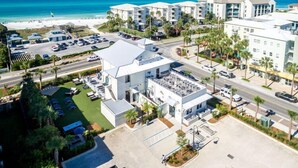 A coastal hotel with multiple buildings, a parking lot, and a view of the beach and ocean.