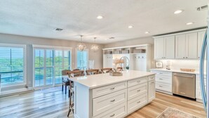 A spacious kitchen with a large island, white cabinetry, and a view through the glass doors.