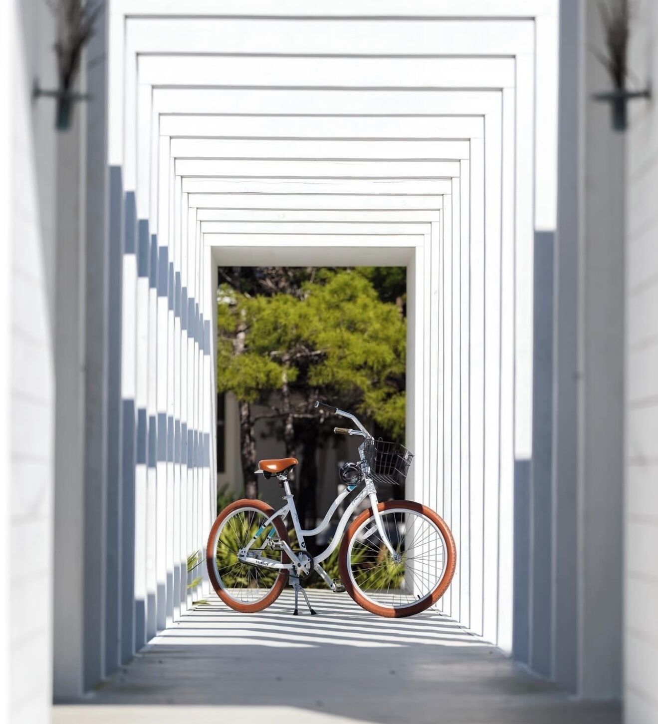 Un vélo est garé dans une structure blanche, de forme géométrique, qui ressemble à un tunnel.