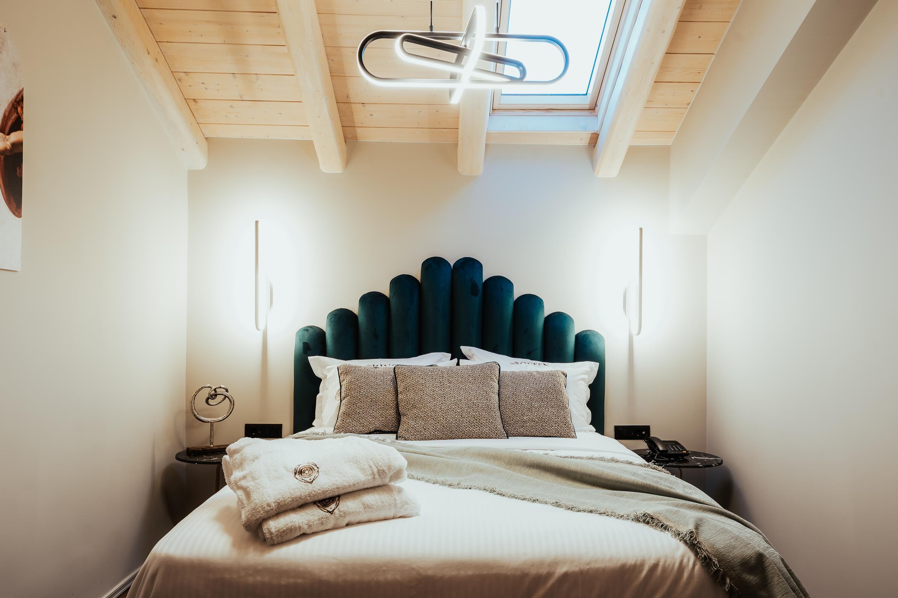 A bedroom with a bed, a headboard, bedside tables, and a skylight.