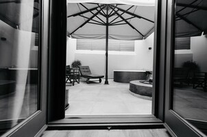 Un espacio de sala moderno y abierto con un paraguas grande, un sillón y un área de estar circular.